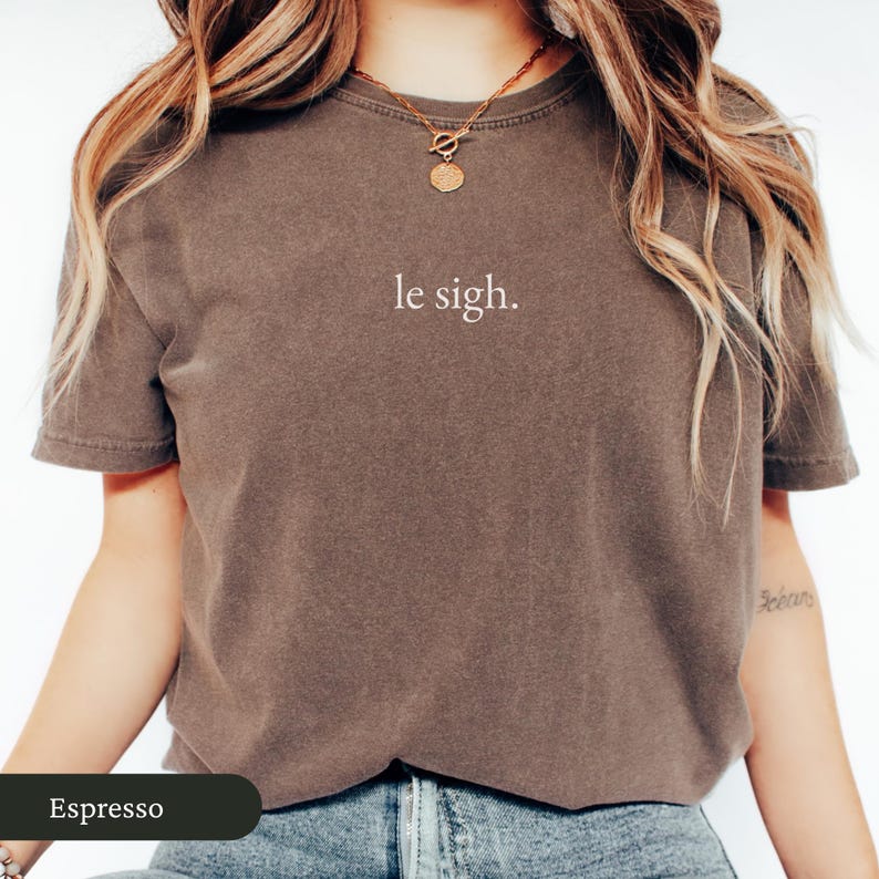 Pu&ograve; includere: T-shirt color espresso con la scritta "le sigh." La maglietta a maniche corte &egrave; di colore unito e ha un girocollo. La maglietta &egrave; realizzata in un materiale morbido ed &egrave; adatta per l'abbigliamento casual.