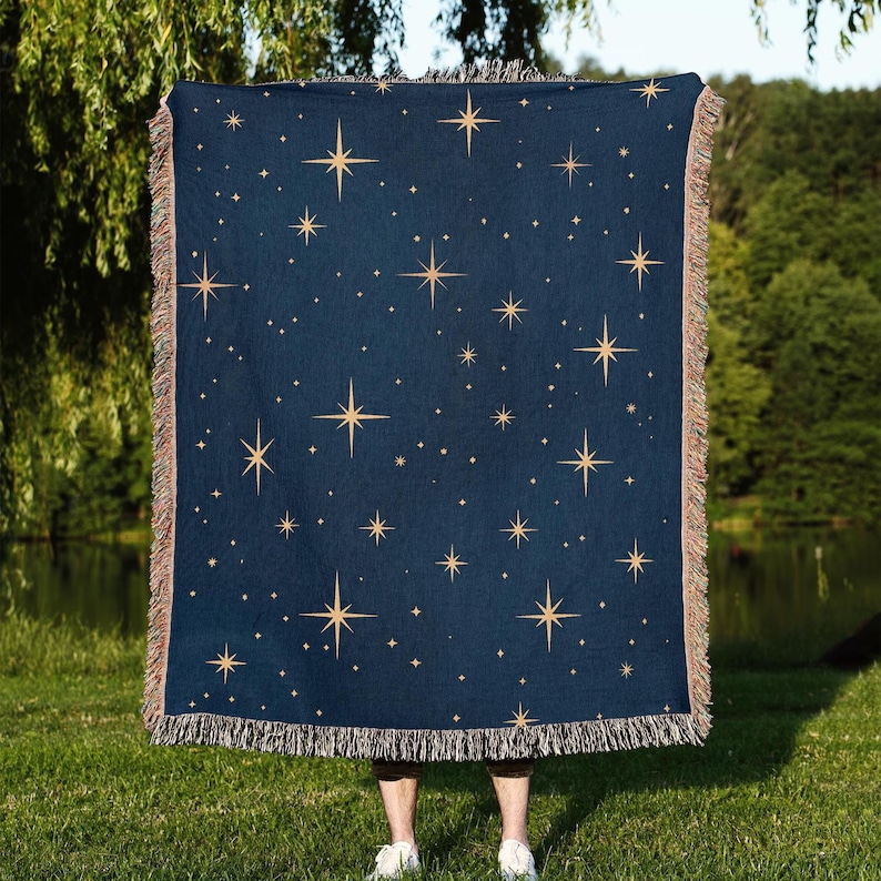 Puede incluir: Una manta azul marino con un patr&oacute;n de estrellas celestiales. La manta presenta estrellas doradas de varios tama&ntilde;os dispersas por la tela. Los bordes est&aacute;n acabados con un ribete de flecos, a&ntilde;adiendo un toque decorativo.