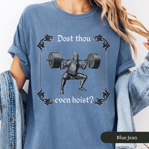 Pode incluir: Uma camiseta azul com um cavaleiro medieval levantando pesos. O texto na camiseta diz "Dost thou even hoist?"
