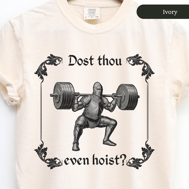 Pode incluir: Uma camiseta branca com uma ilustra&ccedil;&atilde;o em preto e branco de um cavaleiro levantando pesos. O texto "Dost thou even hoist?" est&aacute; impresso na camiseta.