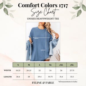 May include: A size chart for a unisex heavyweight tee shirt. The chart shows measurements in inches for width and length, ranging from size S to 3XL. The shirt is a light blue colour. The text "Comfort Colors 1717" and "Feline & Fable" are also visible.