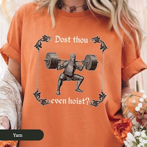 Pode incluir: Camiseta laranja com um gr&aacute;fico de um cavaleiro levantando uma barra. O texto na camiseta diz "Dost thou even hoist?"