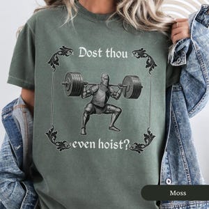 Pode incluir: Uma camiseta verde com um cavaleiro medieval levantando pesos. O texto na camiseta diz "Dost thou even hoist?"