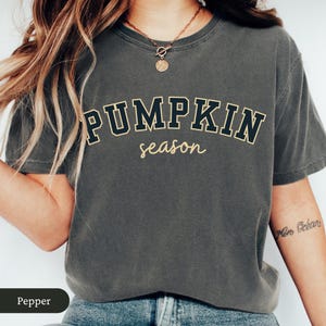 Pu&ograve; includere: T-shirt grigio scuro con la scritta "PUMPKIN season" in blu scuro e oro, in stile collegiale. La maglietta ha una vestibilit&agrave; ampia, ideale per la stagione autunnale.