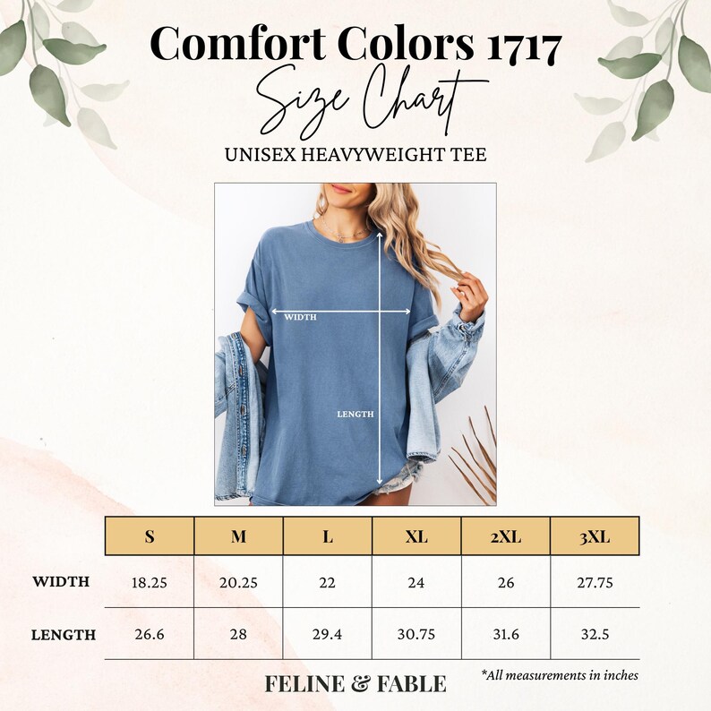 May include: A size chart for a unisex heavyweight tee shirt. The chart shows measurements in inches for width and length, ranging from size small to 3XL. The shirt is a dusty blue color. The brand name is Feline & Fable.