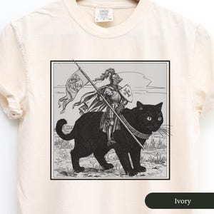 May include: A black and white illustration of a knight riding a black cat. The knight is wearing armor and holding a sword. The cat is wearing a collar and has a crown on its head. The illustration is set against a white background.