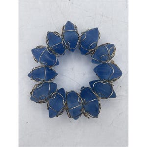 May include: A circular bracelet composed of eleven individual blue frosted glass beads, each encased in a decorative silver-toned wire wrapping. The beads are arranged in a continuous ring, connected by the intricate metal wire structure.