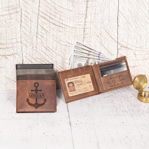 May include: Leather wallets in shades of brown and gray are displayed. One wallet is open, revealing a driver's license and the inscription "I love you to the moon and back." Another wallet features an anchor design and the name "ADRIAN."