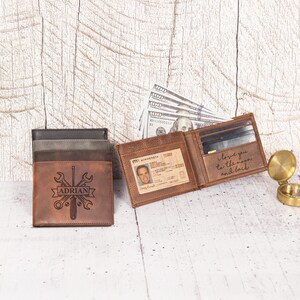 May include: A stack of leather wallets in shades of brown and gray. One wallet is open, displaying a driver's license and the engraved phrase "I love you to the moon and back." The front wallet is engraved with tools and the name "ADRIAN."