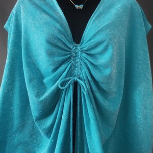 May include: A turquoise blue, lightweight, halter top with a gathered neckline and a drawstring tie at the centre.