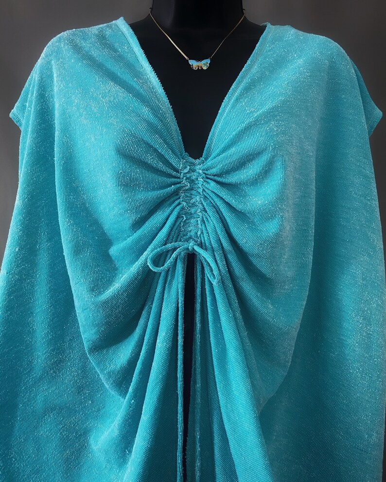 May include: A turquoise blue, lightweight, halter top with a gathered neckline and a drawstring tie at the centre.