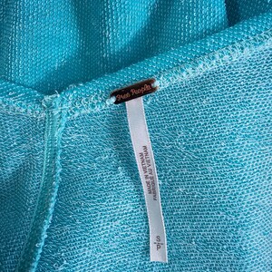 May include: A turquoise blue garment tag with the text "Free People" and "Made in Vietnam / Fabrique au Vietnam" printed on it.
