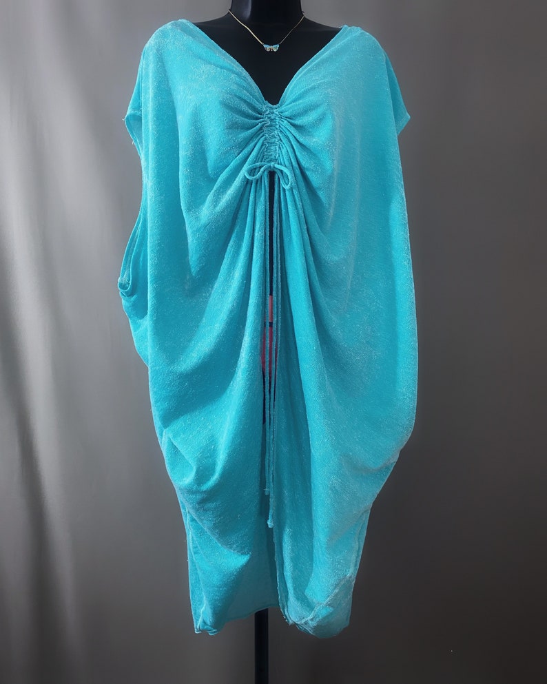May include: A turquoise blue, loose-fitting, sleeveless top with a drawstring neckline.