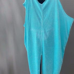 May include: A light blue, loose-fitting, sleeveless tunic with a V-neckline and a centre back seam.