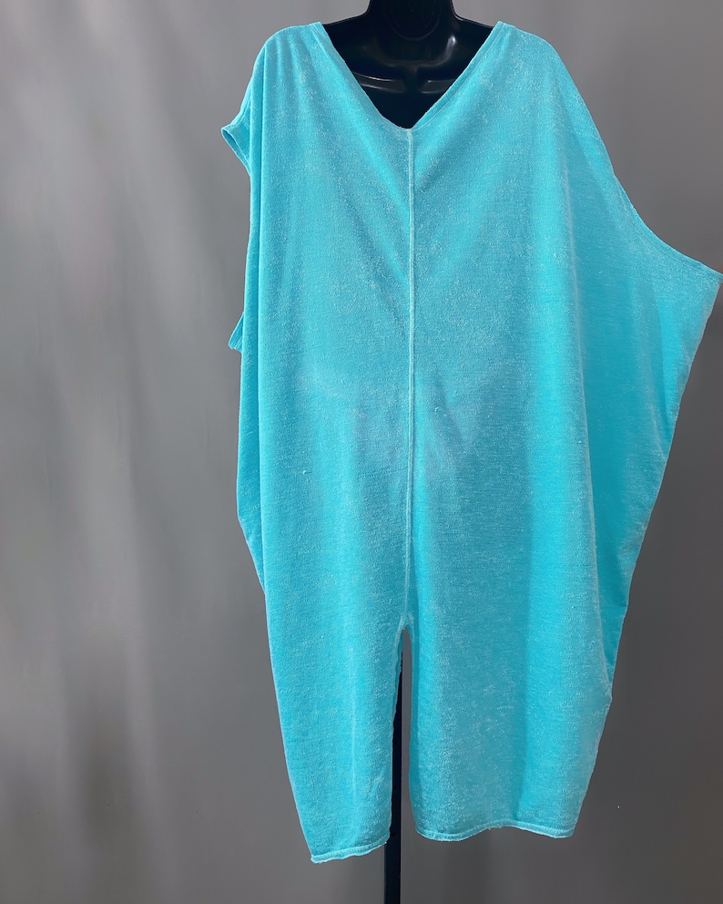 May include: A light blue, loose-fitting, sleeveless tunic with a V-neckline and a centre back seam.