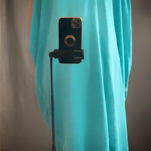 May include: A turquoise sleeveless tunic top with a straight neckline. The top is loose fitting and has a flowing silhouette.
