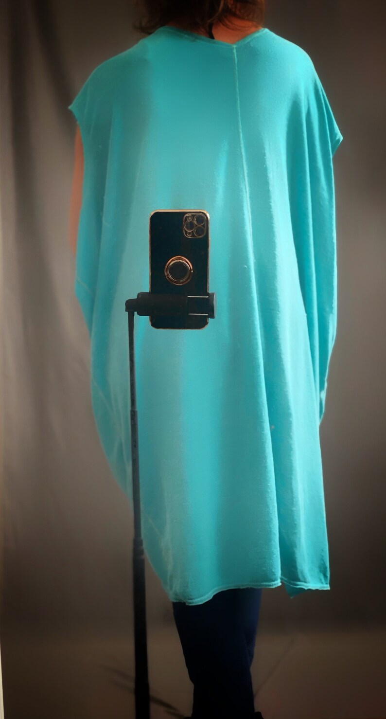 May include: A turquoise sleeveless tunic top with a straight neckline. The top is loose fitting and has a flowing silhouette.