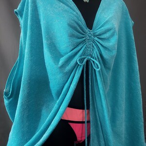 May include: A turquoise blue, lightweight, sheer cover-up with a drawstring neckline and a loose, flowing fit.