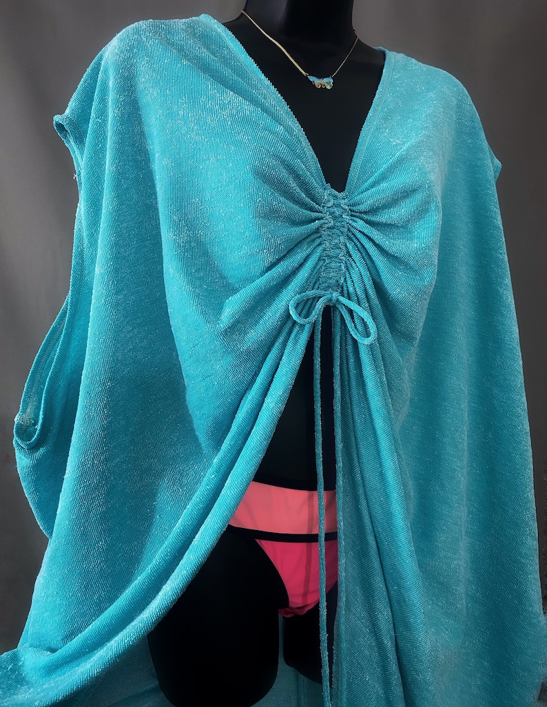 May include: A turquoise blue, lightweight, sheer cover-up with a drawstring neckline and a loose, flowing fit.
