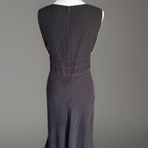 Puede incluir: Vestido negro sin mangas exhibido en un maniqu&iacute;. El vestido presenta un escote en V, una cintura entallada con costuras horizontales y una falda fluida que llega hasta la pantorrilla. El vestido tiene cierre de cremallera en la espalda.