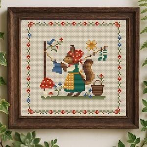 May include: Cross-stitch pattern featuring a squirrel wearing a red and white hat and a green dress, hanging laundry on a clothesline. The squirrel is standing next to a mushroom and a flower pot. The pattern is framed in a brown wooden frame.