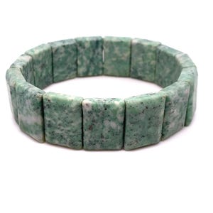 May include: A green and white speckled bracelet. The bracelet is made of rectangular, polished stones. The stones are strung together to form a flexible band. The bracelet is shown on a white background.