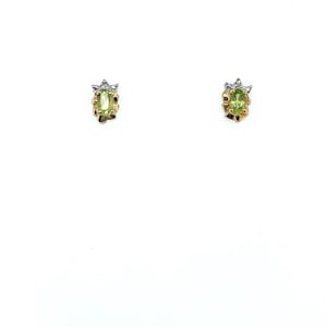 May include: A pair of stud earrings featuring oval-cut peridot gemstones. The earrings have a gold setting with a textured design and small, sparkling accents. The peridot stones are a vibrant green color.