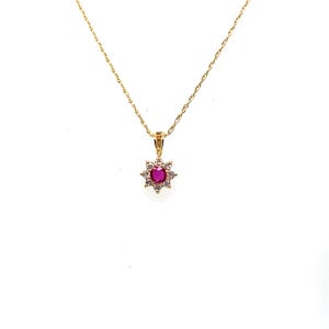 May include: A gold necklace featuring a delicate chain and a pendant shaped like a star or flower. The center of the pendant contains a round, vibrant pink gemstone, which is surrounded by a halo of small, clear, sparkling white stones.