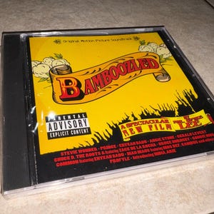 May include: A CD case featuring the "Bamboozled" original motion picture soundtrack. The cover is predominantly yellow with a banner reading "Bamboozled" in red and black. The CD case has a parental advisory warning.