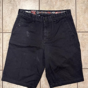 May include: Black shorts with a button closure and side pockets. The shorts have a patterned interior waistband. There are some white stains on the front of the shorts. The shorts are made of a durable material.