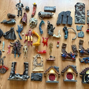 Puede incluir: Una colección de figuras de acción y accesorios, incluyendo personajes como Iron Man y Wolverine. Las figuras están en varias poses y colores, con diseños detallados. Los accesorios incluyen armas, capas y elementos de construcción.