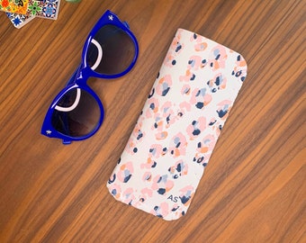 May include: A white and pink leopard print glasses case with the initials "AS" on the front. The case is made of a soft, durable material and is perfect for protecting your glasses.