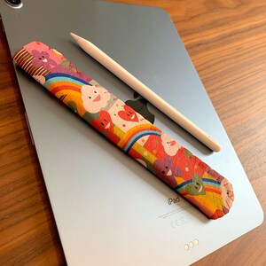 May include: A colorful patterned iPad pencil grip with a white Apple Pencil on a silver iPad.