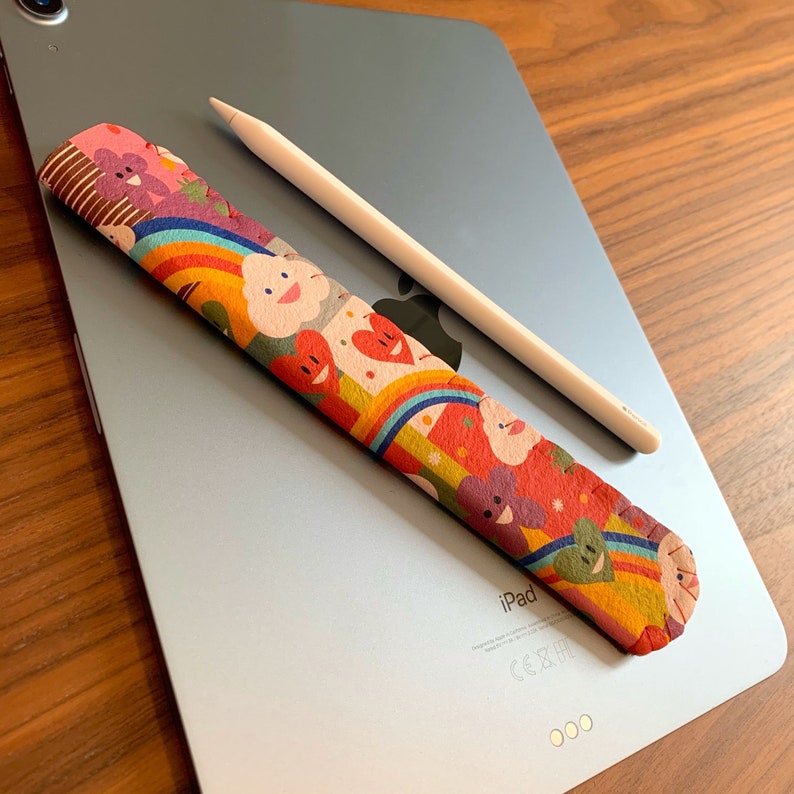 May include: A colorful patterned iPad pencil grip with a white Apple Pencil on a silver iPad.