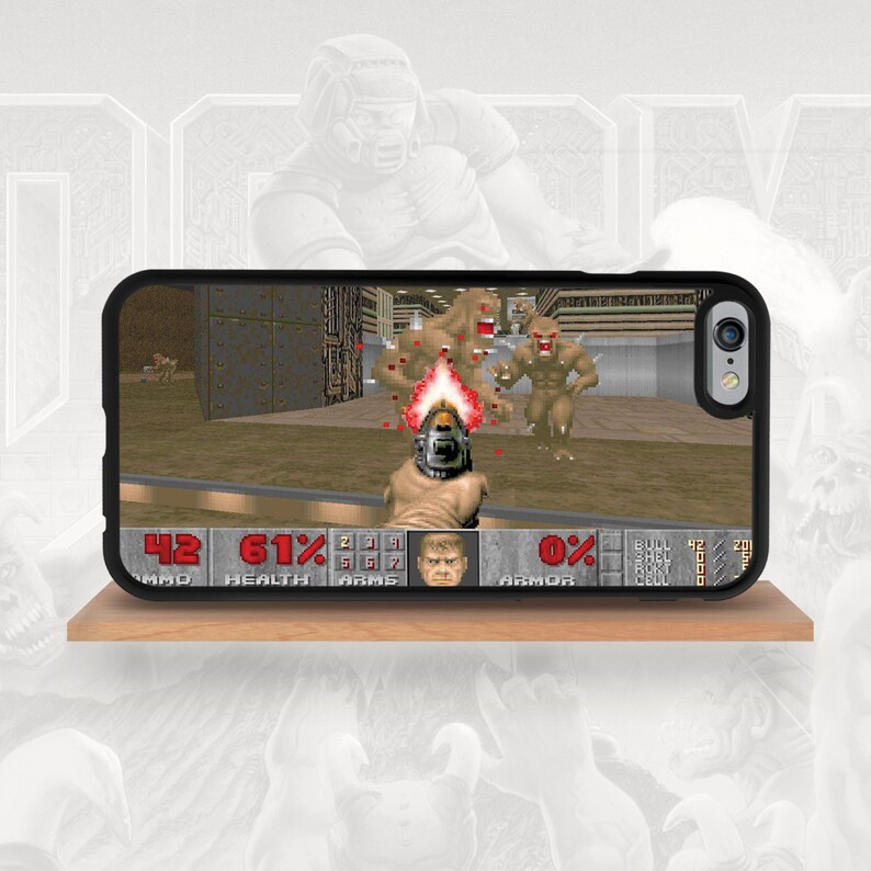 May include: Black phone case featuring a screenshot from the classic video game Doom. The game's interface displays health, ammo, and armor levels. The case shows a first-person shooter perspective with pixelated monsters and a weapon firing.