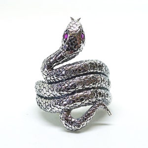 May include: A silver snake ring with pink gemstones for eyes. The snake is coiled and has a textured surface.