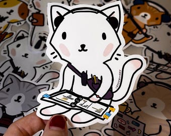 Puede incluir: Pegatina de gato blanco con auriculares negros, una bolsa morada y un cuaderno. El gato tiene mejillas rosadas y está rodeado de otras pegatinas de gatos. La pegatina tiene el texto "STUCK ON SET".