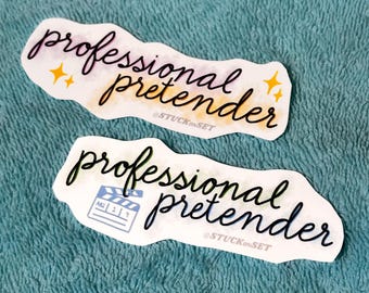 Puede incluir: Dos pegatinas con las palabras "professional pretender" en una fuente manuscrita. Una pegatina tiene un icono de claqueta de cine. Las pegatinas tienen un fondo de acuarela con acentos de estrellas amarillas. También está presente el texto "@STUCKonSET".
