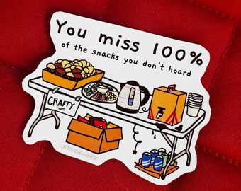 Puede incluir: Una pegatina blanca con el texto "You miss 100% of the snacks you don't hoard." La imagen muestra una mesa con aperitivos, una tetera y una caja con la etiqueta "Crafty". La pegatina está sobre un fondo rojo.