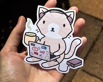 Puede incluir: Una pegatina con un gato de dibujos animados con auriculares y trabajando en un portátil. El gato es de color marrón claro con detalles blancos y sostiene una taza de café. Hay una pequeña caja morada al lado del gato.
