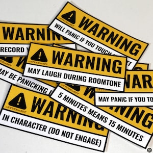 Puede incluir: Un conjunto de pegatinas de advertencia amarillas y negras con frases humorísticas. Las pegatinas presentan un símbolo de exclamación negro y la palabra "WARNING" en blanco. Las frases incluyen "Will Panic If You Touch" y "May Laugh During Roomtone".