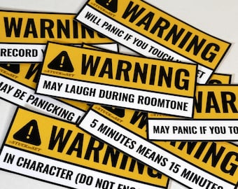 Puede incluir: Un conjunto de pegatinas de advertencia amarillas y negras con frases humorísticas. Las pegatinas presentan un símbolo de exclamación negro y la palabra "WARNING" en blanco. Las frases incluyen "Will Panic If You Touch" y "May Laugh During Roomtone".