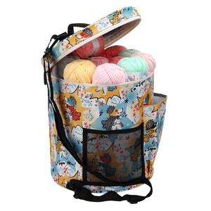 Puede incluir: Una bolsa de almacenamiento de hilo amarilla, azul y blanca con estampado de erizo. La bolsa tiene una parte superior con cremallera y una correa para el hombro. La bolsa est&aacute; llena de ovillos de hilo de colores.
