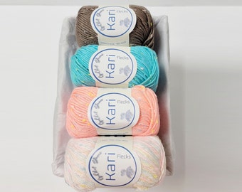 May include: A set of four yarn skeins in a white basket. The skeins are brown, teal, peach, and a multi-colored blend. Each skein has a label that reads "Guchet Yarn Kari Flecks".