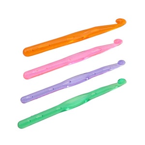 Pu&ograve; includere: Quattro uncini da uncinetto in plastica colorati, arancione, rosa, viola e verde, sono disposti in fila su uno sfondo bianco.