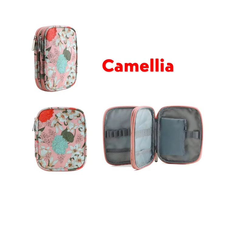 May include: A pink floral needlepoint organizer with a zipper closure. The organizer is open to reveal a gray interior with multiple compartments and a small zippered pouch. The text "Camellia" is printed in red on a white background.