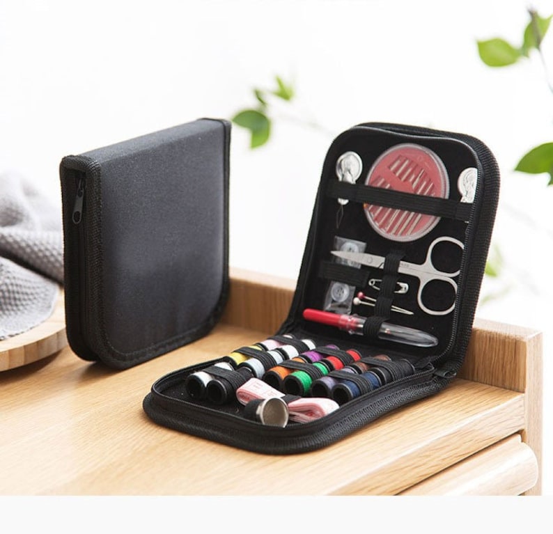 May include: A black zippered case containing a selection of sewing essentials, such as needles, thread, a thimble, and scissors.