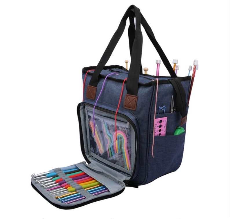 May include: A blue canvas tote bag with multiple pockets and compartments for storing knitting needles and other supplies. The bag has a zipper closure and a top handle.