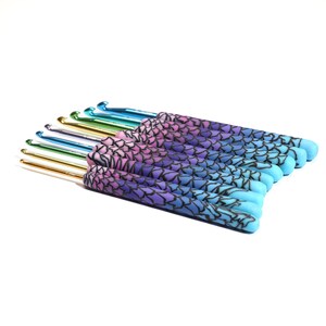 May include: A set of 12 crochet hooks with colorful, gradient-patterned handles. The handles are a mix of pink, purple, blue, and teal. The hooks are made of metal and have a shiny finish.
