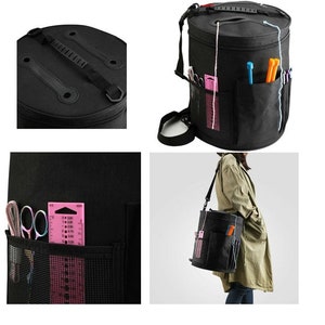 Puede incluir: Bolso de lona negro para hilo de lana con m&uacute;ltiples bolsillos y una parte superior con cremallera. El bolso tiene una correa para el hombro y un asa. El bolso est&aacute; lleno de hilo, agujas y otros suministros de tejido.